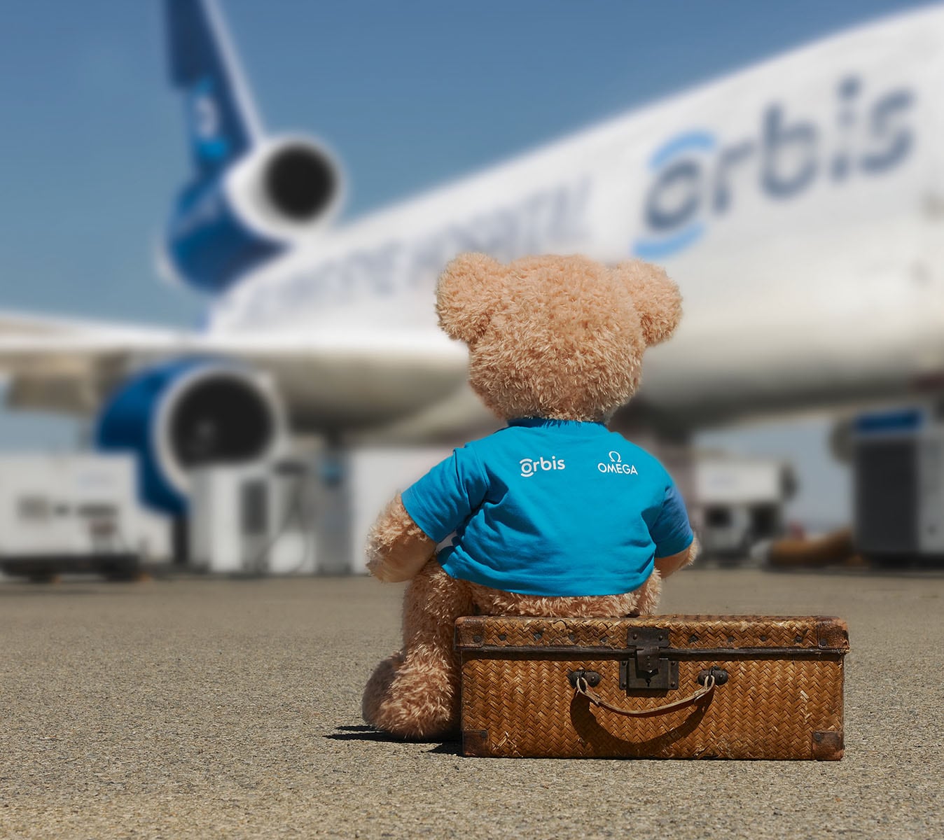 The Orbis teddy bear mascot sitting next to the Orbis Flying Eye Hospital aircraft