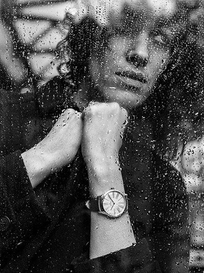 Model wearing a De Ville Trésor watch looking through a window full of rain spots